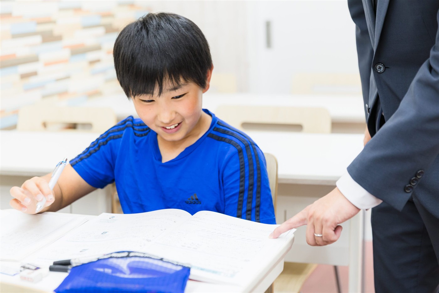 先生に教わりながら問題を解く生徒